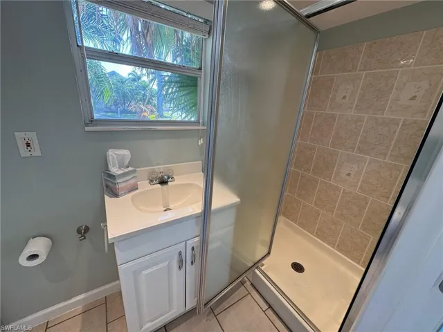 Bathroom featuring tile patterned flooring, vanity, and a shower with door