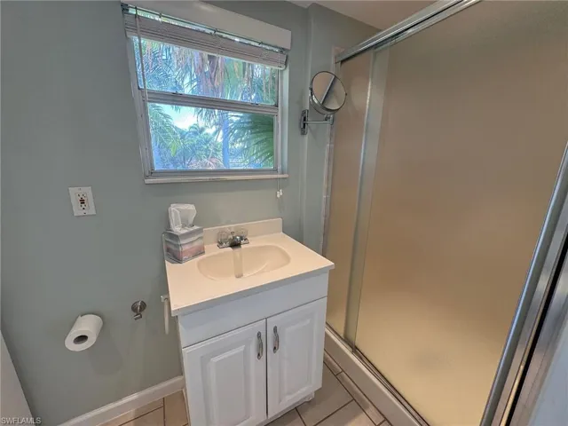 Bathroom with tile patterned flooring, vanity, and an enclosed shower