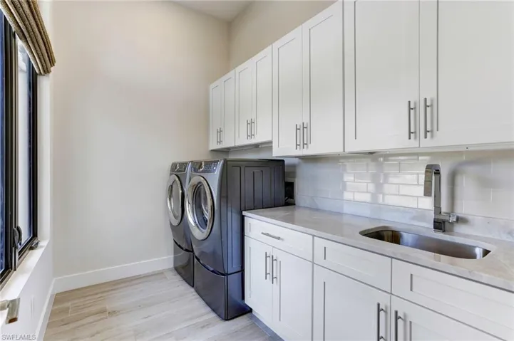 Bright laundry room with plenty of workspace and cabinets for storage