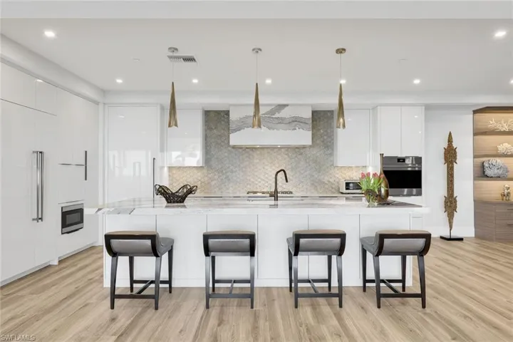 A custom backsplash, oversized island, and top-tier appliances define this chef-inspired kitchen, blending modern elegance with exceptional functionality.