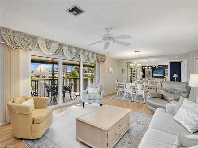 Living area with ceiling fan, light wood-type flooring, and a chandelier