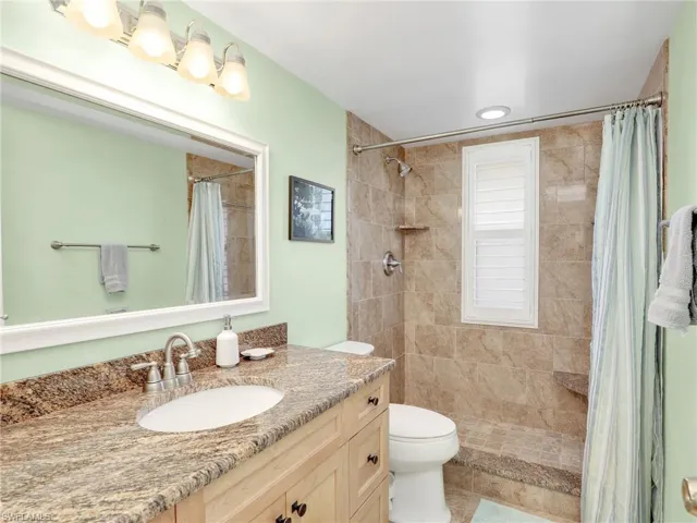 Full bath featuring vanity, tiled shower, and recessed lighting