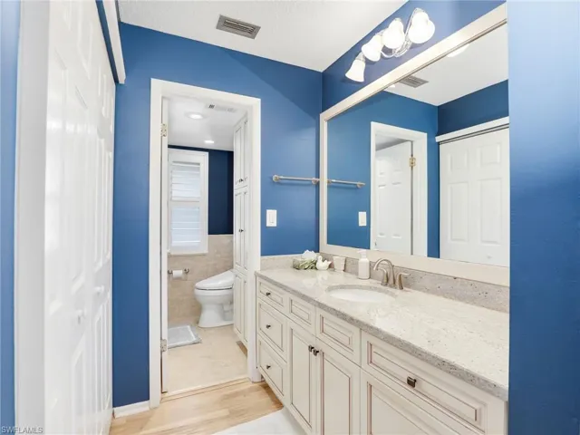 Bathroom with vanity, wood finished floors, and tile walls