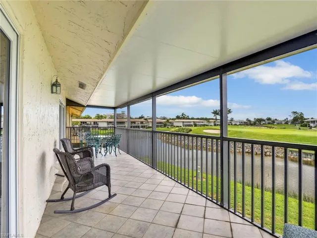 Sunroom featuring view of golf course, a water view, and a residential view