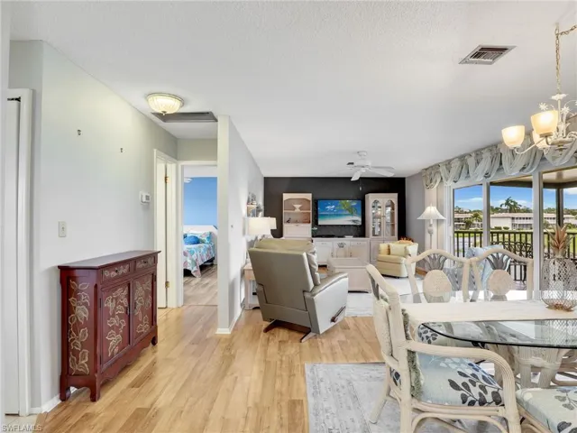 Dining space with a chandelier, light wood-style flooring, a textured ceiling, and a ceiling fan