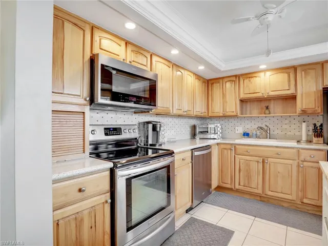 Kitchen with stainless steel appliances, light brown cabinetry, ornamental molding, recessed lighting, and backsplash