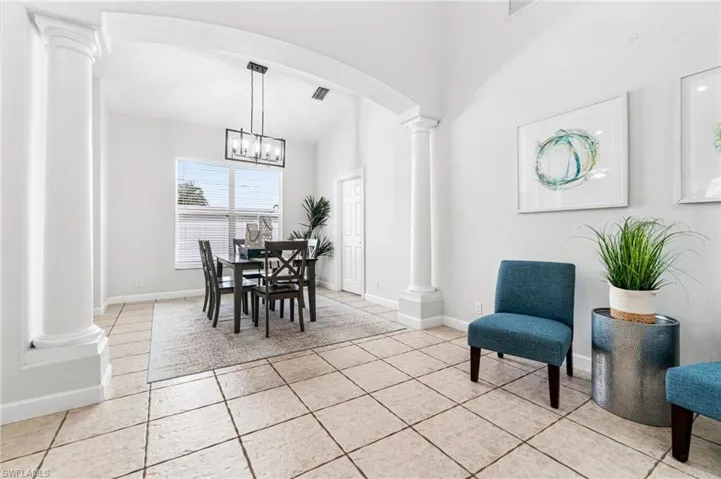 Tiled dining area featuring an inviting chandelier and ornate columns