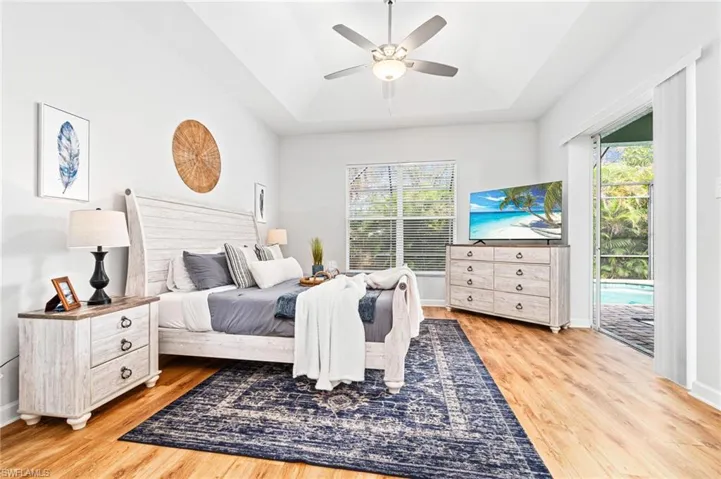 Bedroom with ceiling fan, access to exterior, light hardwood / wood-style flooring, and multiple windows