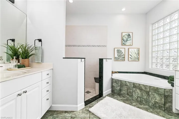 Bathroom with tile flooring, shower with separate bathtub, and vanity