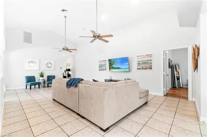 Living room with high vaulted ceiling, ceiling fan, and light hardwood / wood-style flooring