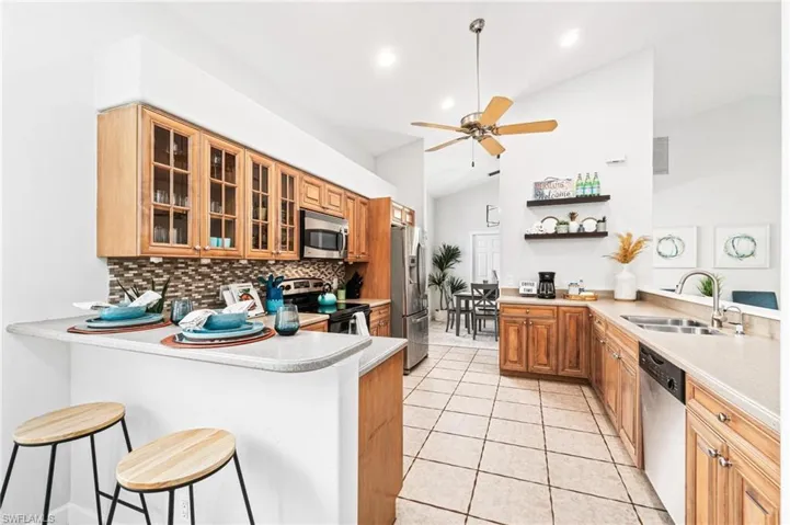 Kitchen featuring a kitchen breakfast bar, kitchen peninsula, stainless steel appliances, sink, and lofted ceiling