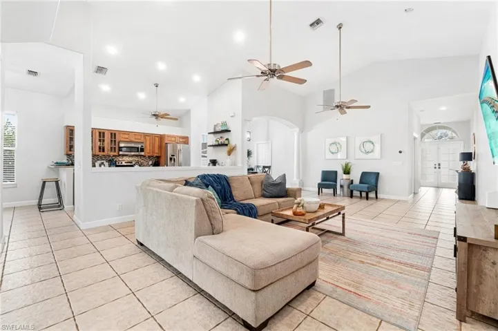 Living room featuring high vaulted ceiling, ceiling fan, and light tile floors