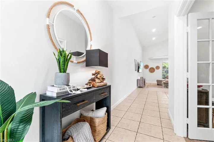 Corridor featuring light tile floors and lofted ceiling