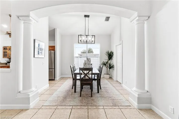 Tiled dining area with a chandelier and decorative columns