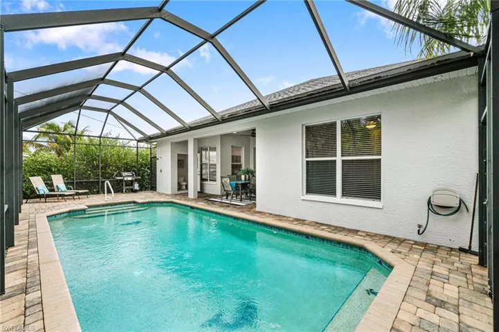 View of swimming pool featuring glass enclosure, a patio area, and area for grilling