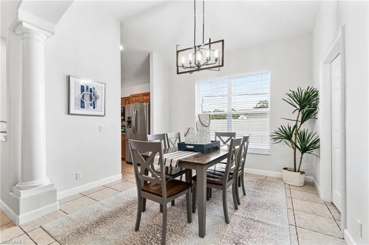 Dining space with a chandelier, light tile flooring, and decorative columns