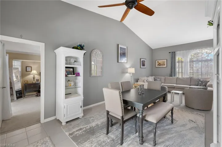 Tiled dining room with ceiling fan and high vaulted ceiling