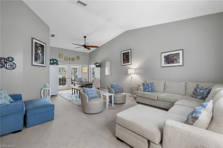 Living room featuring lofted ceiling, light colored carpet, and ceiling fan