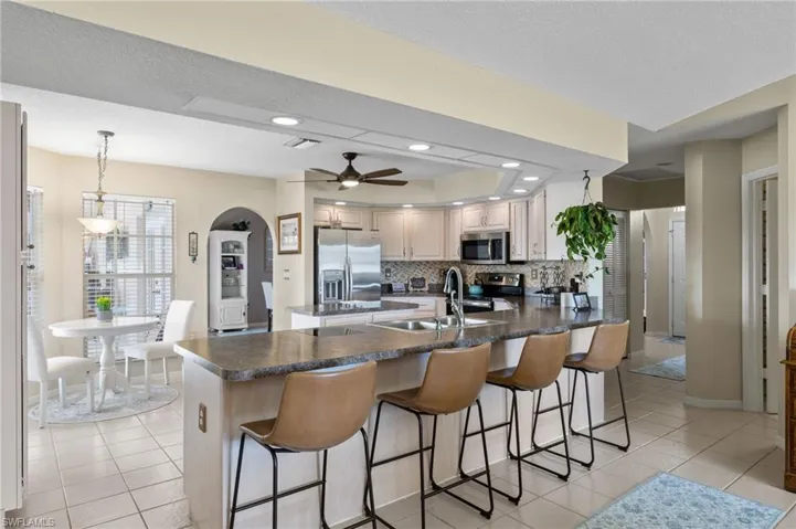 Kitchen featuring sink, decorative light fixtures, appliances with stainless steel finishes, a breakfast bar area, and decorative backsplash