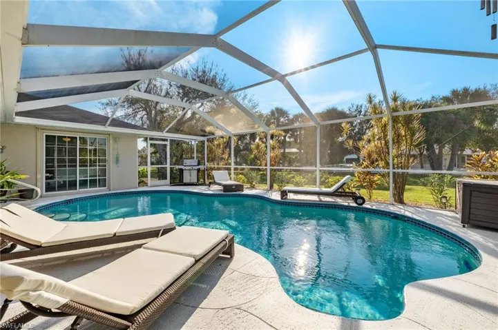 View of pool featuring glass enclosure and a patio area