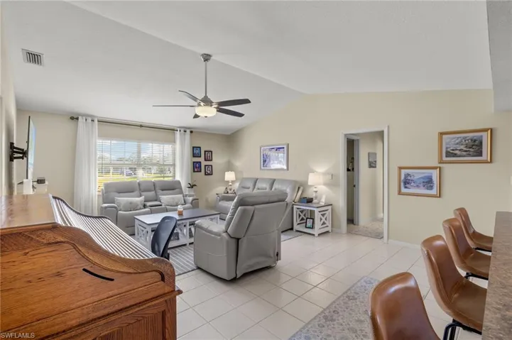 Tiled living room with lofted ceiling and ceiling fan