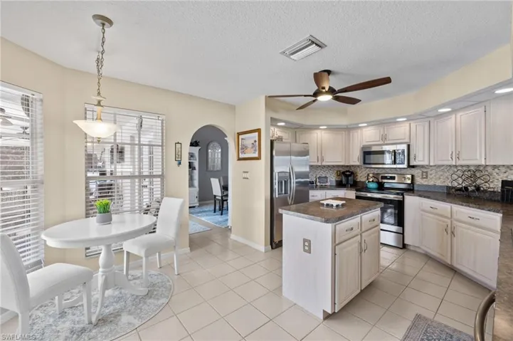 Kitchen featuring appliances with stainless steel finishes, decorative light fixtures, a center island, and a textured ceiling