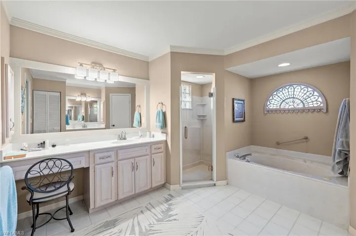 Bathroom with ornamental molding, tile patterned floors, vanity, and shower with separate bathtub