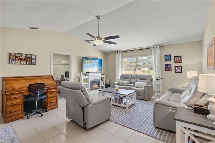 Tiled living room with ceiling fan and vaulted ceiling