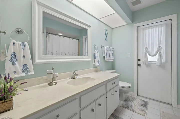 Bathroom featuring vanity, tile patterned flooring, toilet, and door leading to lanai