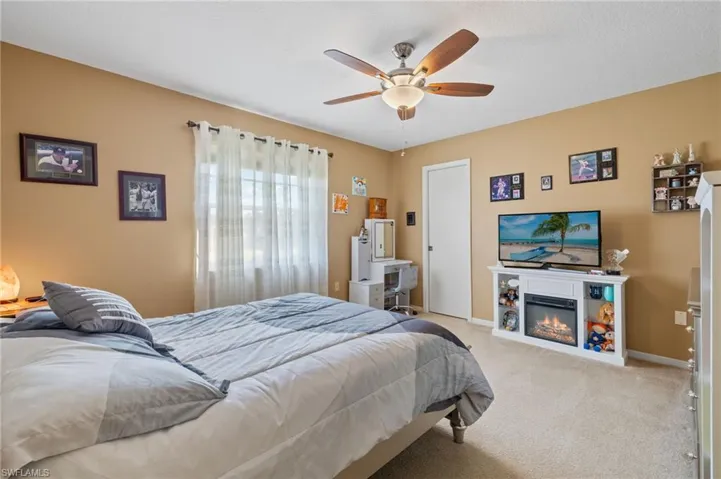 Bedroom with ceiling fan and light carpet
