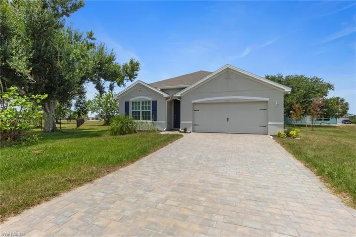 Ranch-style house with a front lawn, stucco siding, driveway, and an attached garage