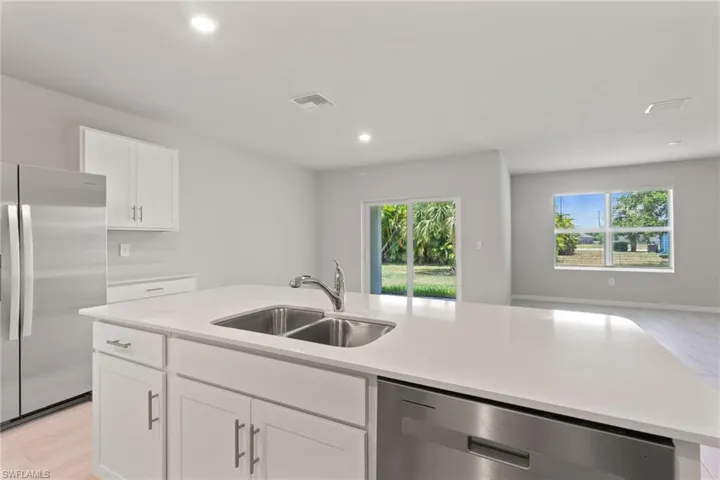 Kitchen featuring white cabinets, stainless steel appliances, light wood finished floors, open floor plan, and recessed lighting