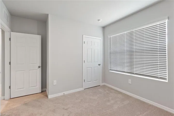 Unfurnished bedroom with light colored carpet and baseboards
