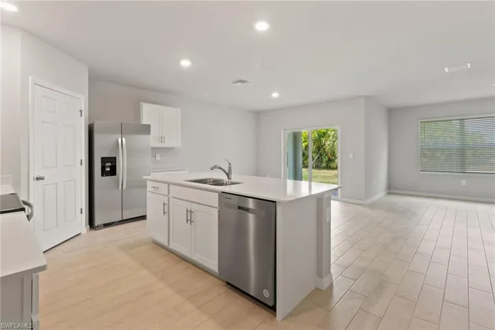 Kitchen featuring stainless steel appliances, light wood-type flooring, an island with sink, white cabinetry, and recessed lighting