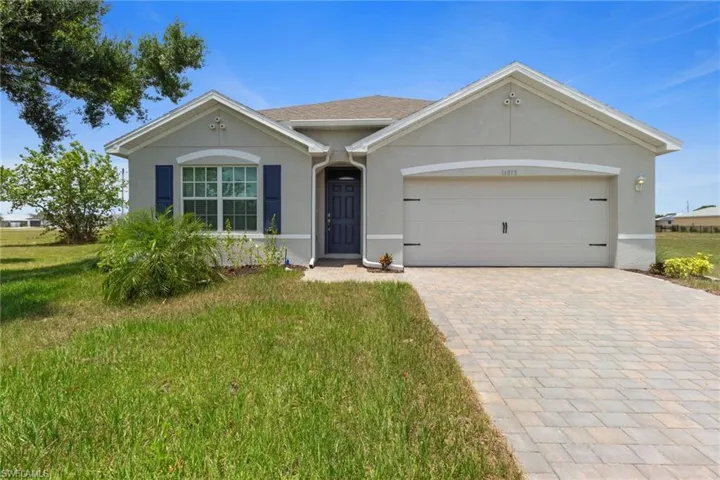 Single story home featuring stucco siding, decorative driveway, a front lawn, and an attached garage
