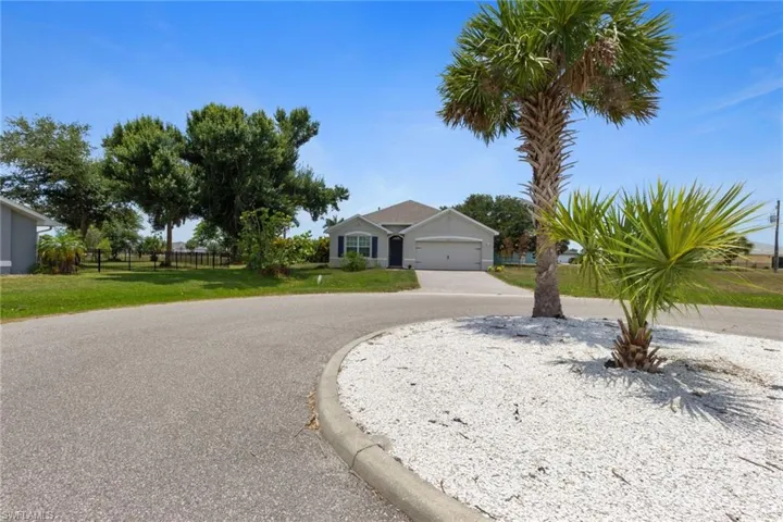 Ranch-style house featuring a front lawn and curved driveway