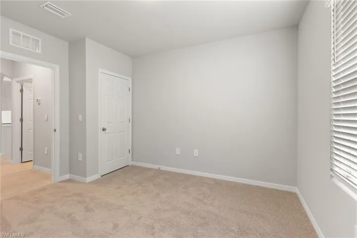 Unfurnished bedroom featuring light colored carpet and baseboards