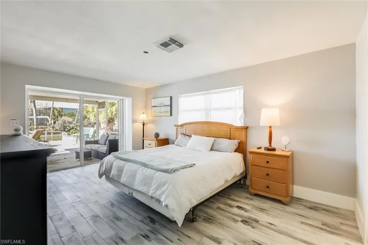 Bedroom with access to outside, light wood finished floors, visible vents, and baseboards