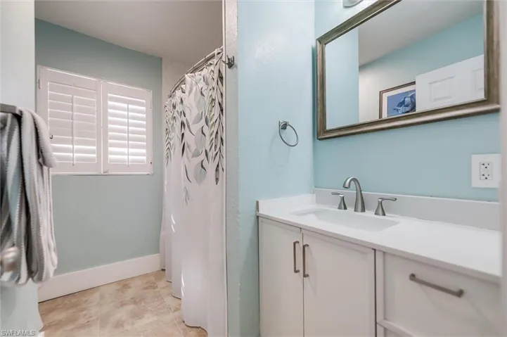 Full bath featuring curtained shower, tile patterned flooring, vanity, and baseboards