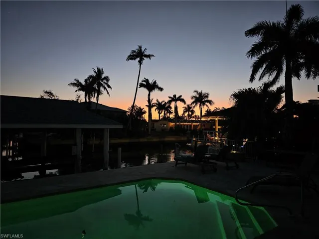 Pool at dusk with a boat dock and a water view