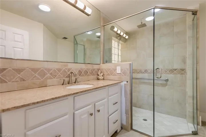 Full bath featuring backsplash, vanity, and a shower stall