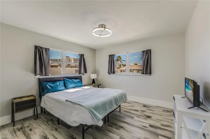 Bedroom with multiple windows, baseboards, and wood finished floors