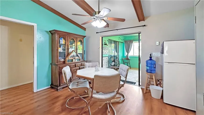 Dining room with ceiling fan, hardwood / wood-style flooring, and vaulted ceiling with beams