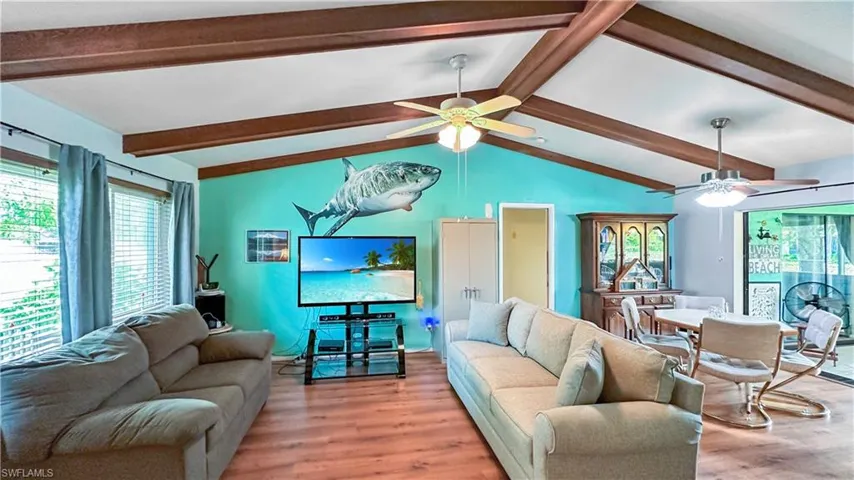 Living room featuring lofted ceiling with beams, ceiling fan, and light hardwood / wood-style floors