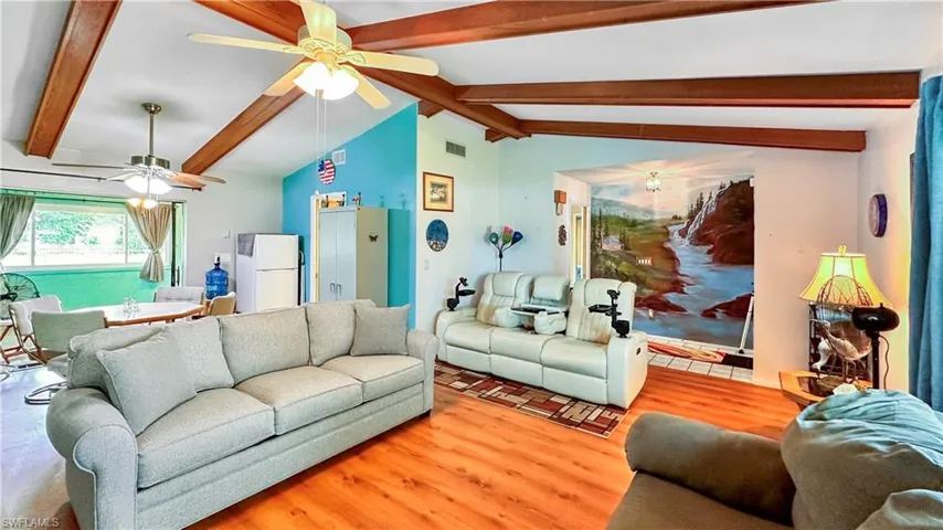 Living room with ceiling fan, hardwood / wood-style flooring, and lofted ceiling with beams