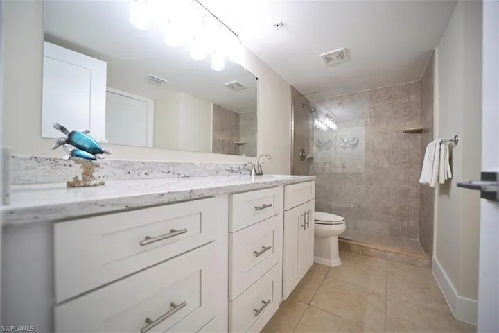 Bathroom with tile patterned floors, vanity, toilet, and tiled shower