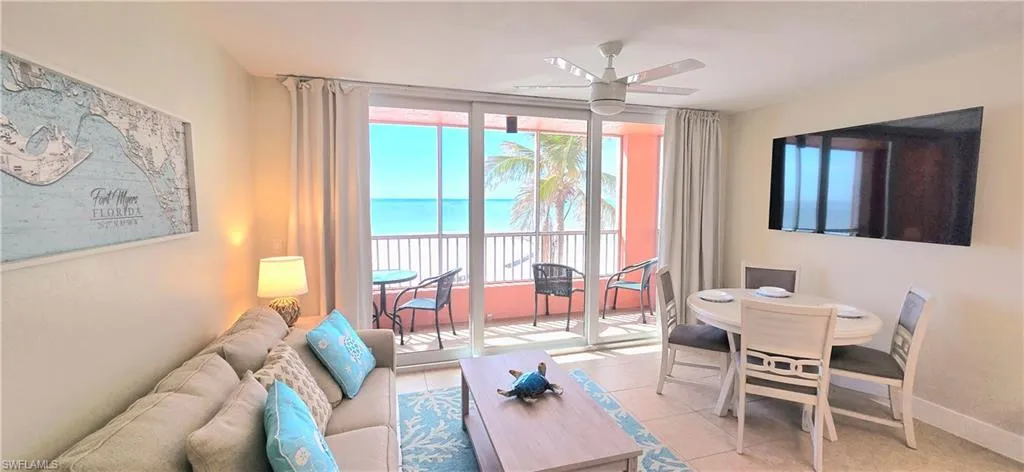 Living room featuring ceiling fan, a water view, and light tile patterned flooring