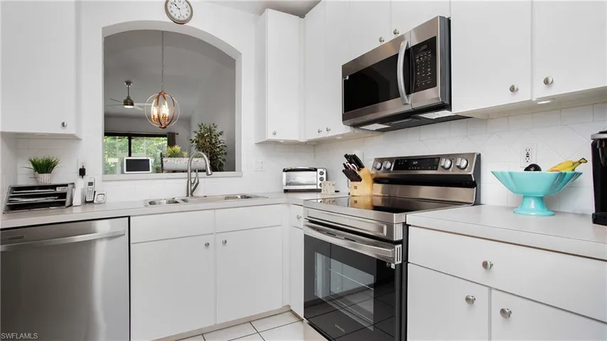 Kitchen with appliances with stainless steel finishes, light countertops, tasteful backsplash, and white cabinetry