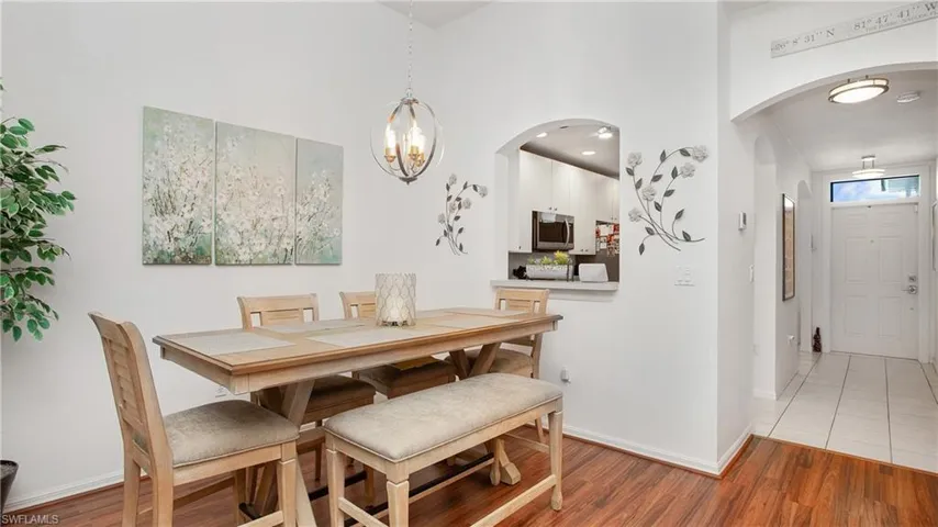 Dining space featuring arched walkways, light wood-type flooring, a chandelier, and a high ceiling