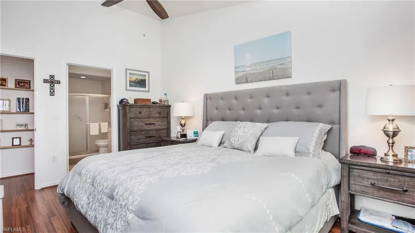 Primary Bedroom featuring dark wood-style flooring, ensuite bathroom, a ceiling fan, and a high ceiling